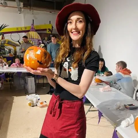 Halloween craft workshop leader holding a decorated pumpkin